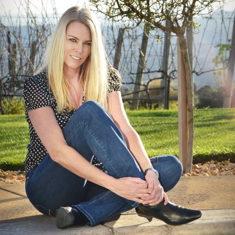 Amy sitting by pool in front of vineyard